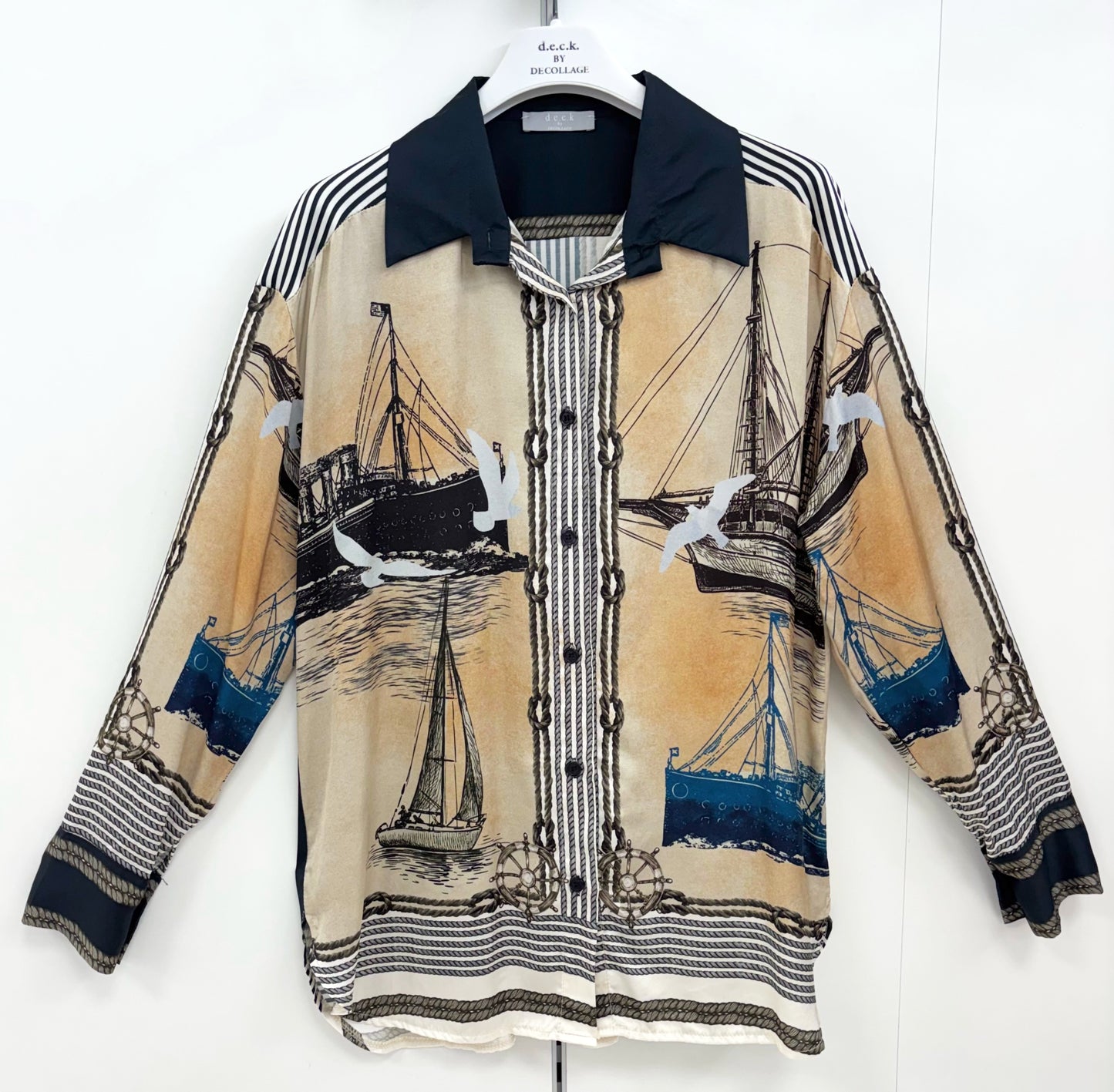 A long-sleeve button-front shirt jacket featuring a nautical print with sailboats, seagulls, and blue water, displayed on a hanger against a white background.
