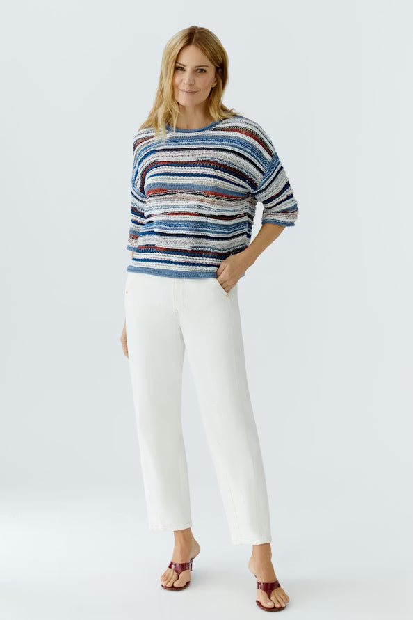 Woman wearing a striped sweater and white pants on a white background
