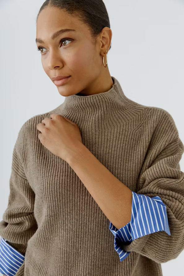 Woman wearing a brown sweater with a white background