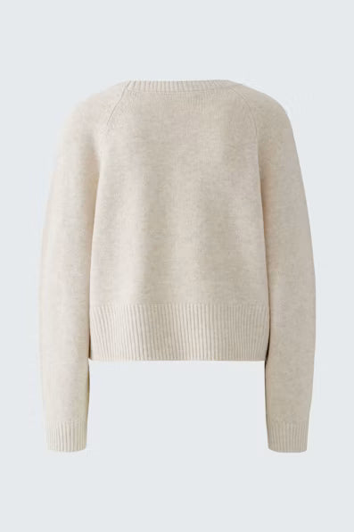 A cropped, long-sleeve knit sweater in a light cream or oatmeal color, shown from the back against a light gray background.