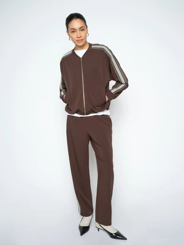 Person wearing a brown tracksuit with white stripes on a white background