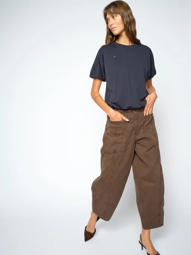 A woman modeling a dark navy blue t-shirt and brown wide-leg cropped pants against a light gray studio background.