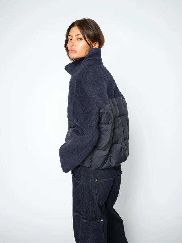 Person wearing a dark blue jacket with quilted design on a white background