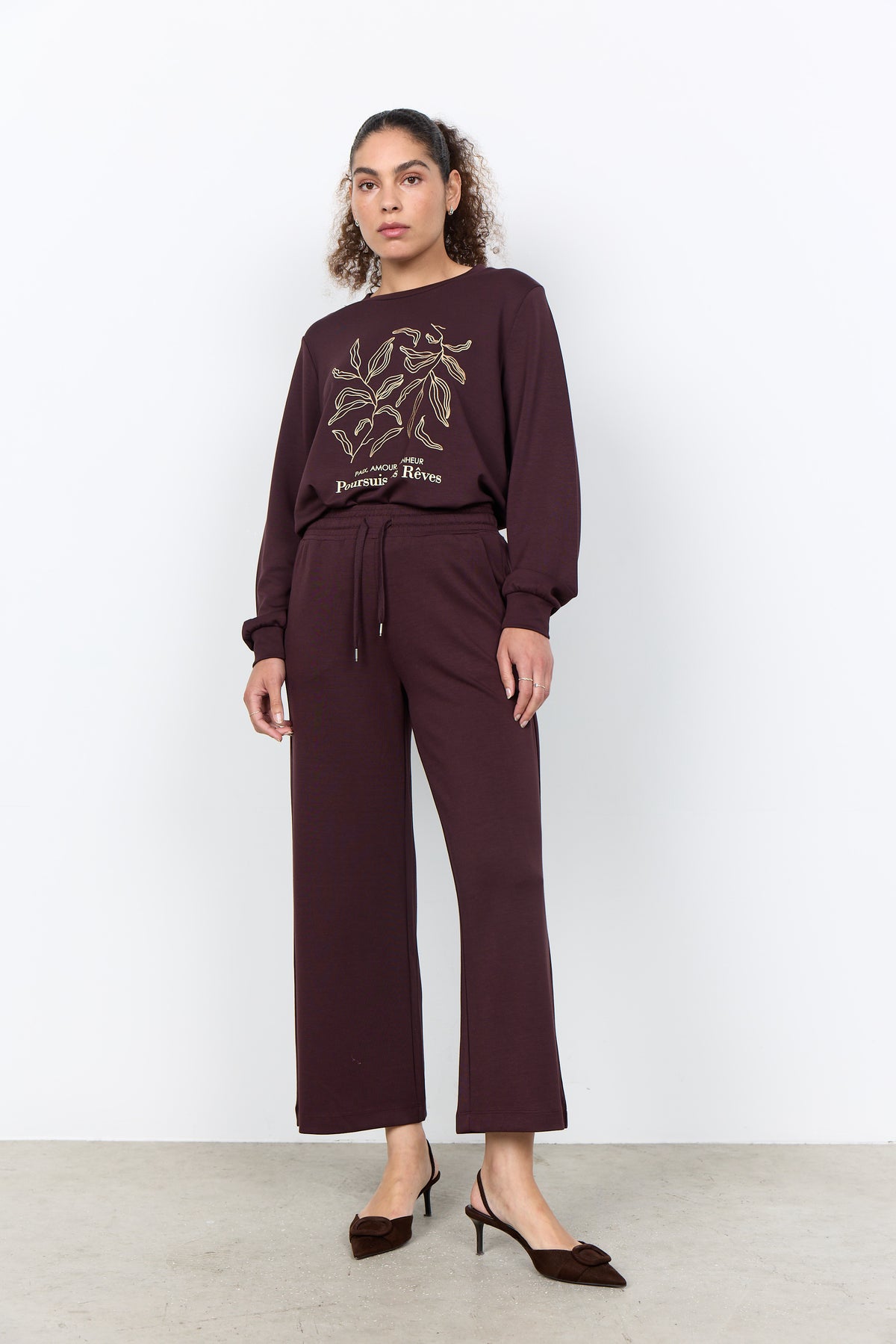 Woman wearing a maroon outfit with a graphic design on a white background