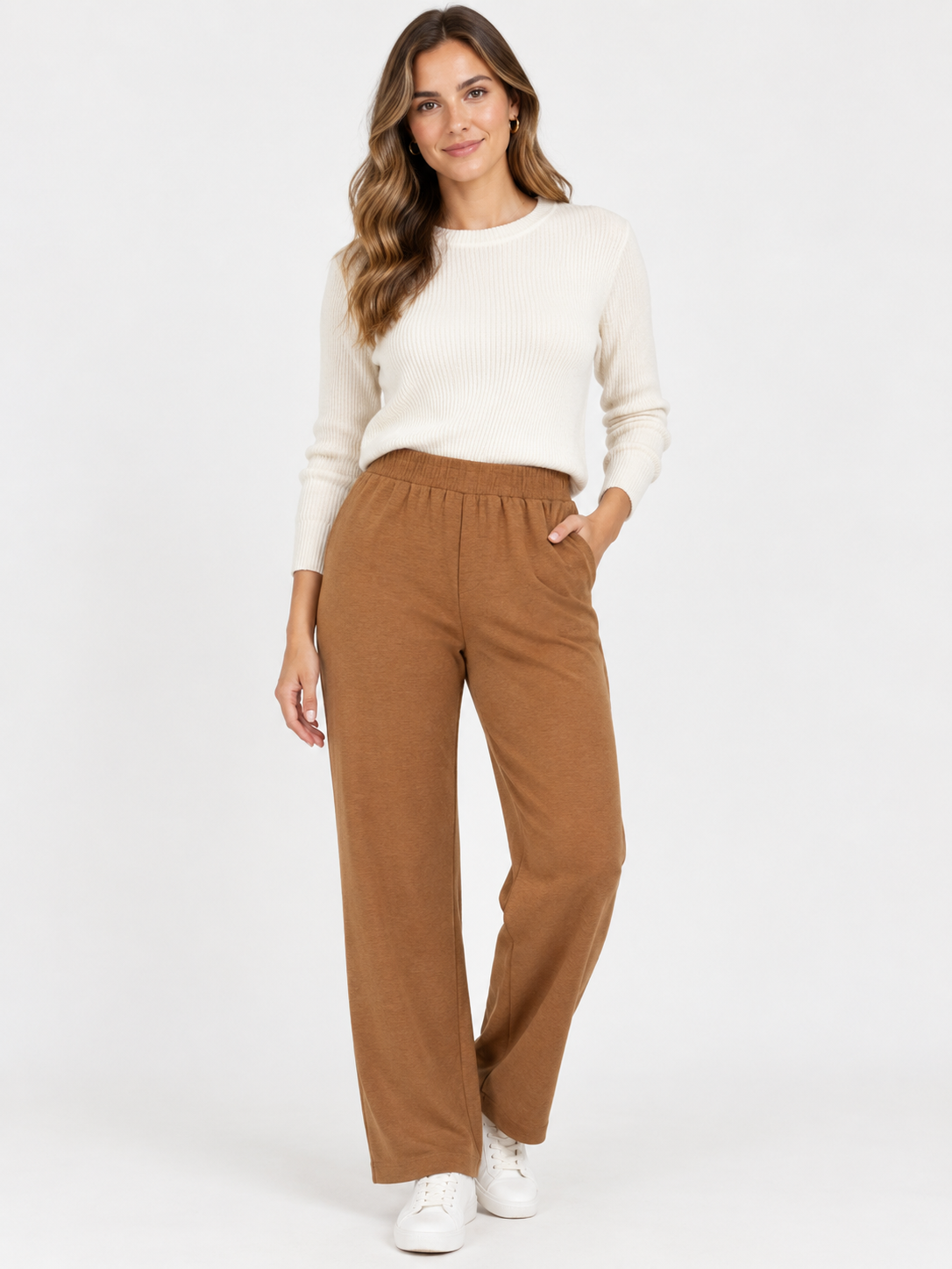 A woman modeling a cream ribbed knit sweater and brown wide-leg corduroy pants against a plain white studio background.