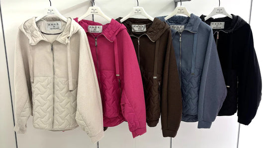 Row of various hoodies on hangers against a white wall