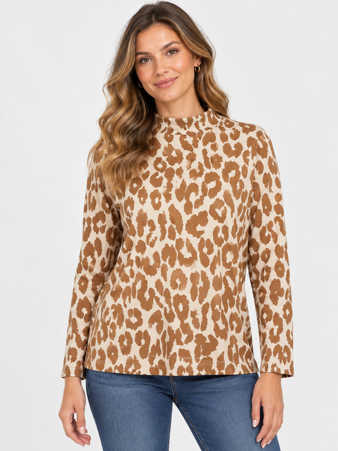 A woman modeling a long-sleeve mock neck top with a brown and beige leopard print pattern, paired with blue jeans, against a light gray studio background.