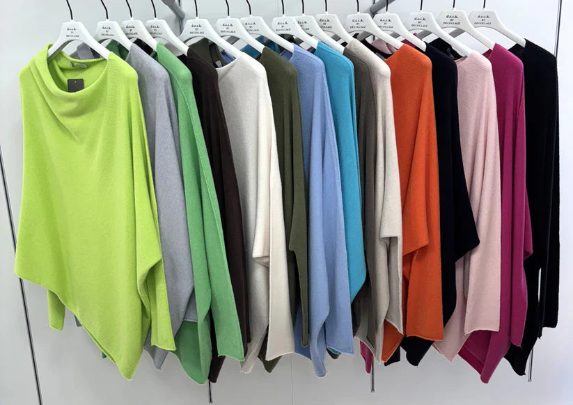 Row of colorful shirts on hangers against a white wall