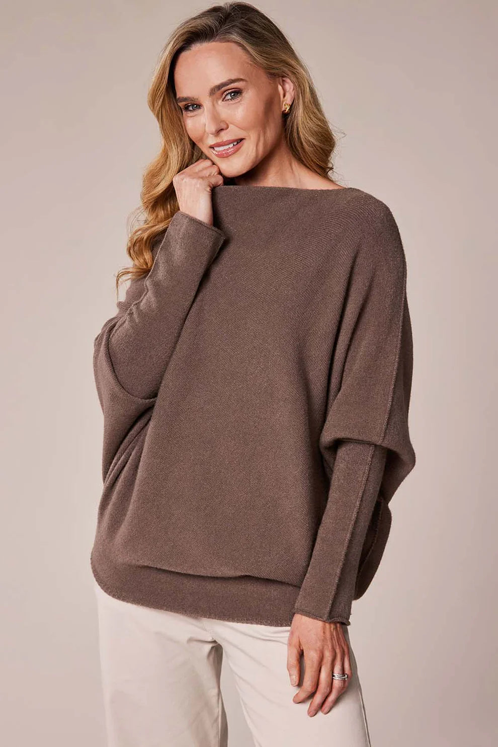 Woman wearing a brown sweater against a beige background