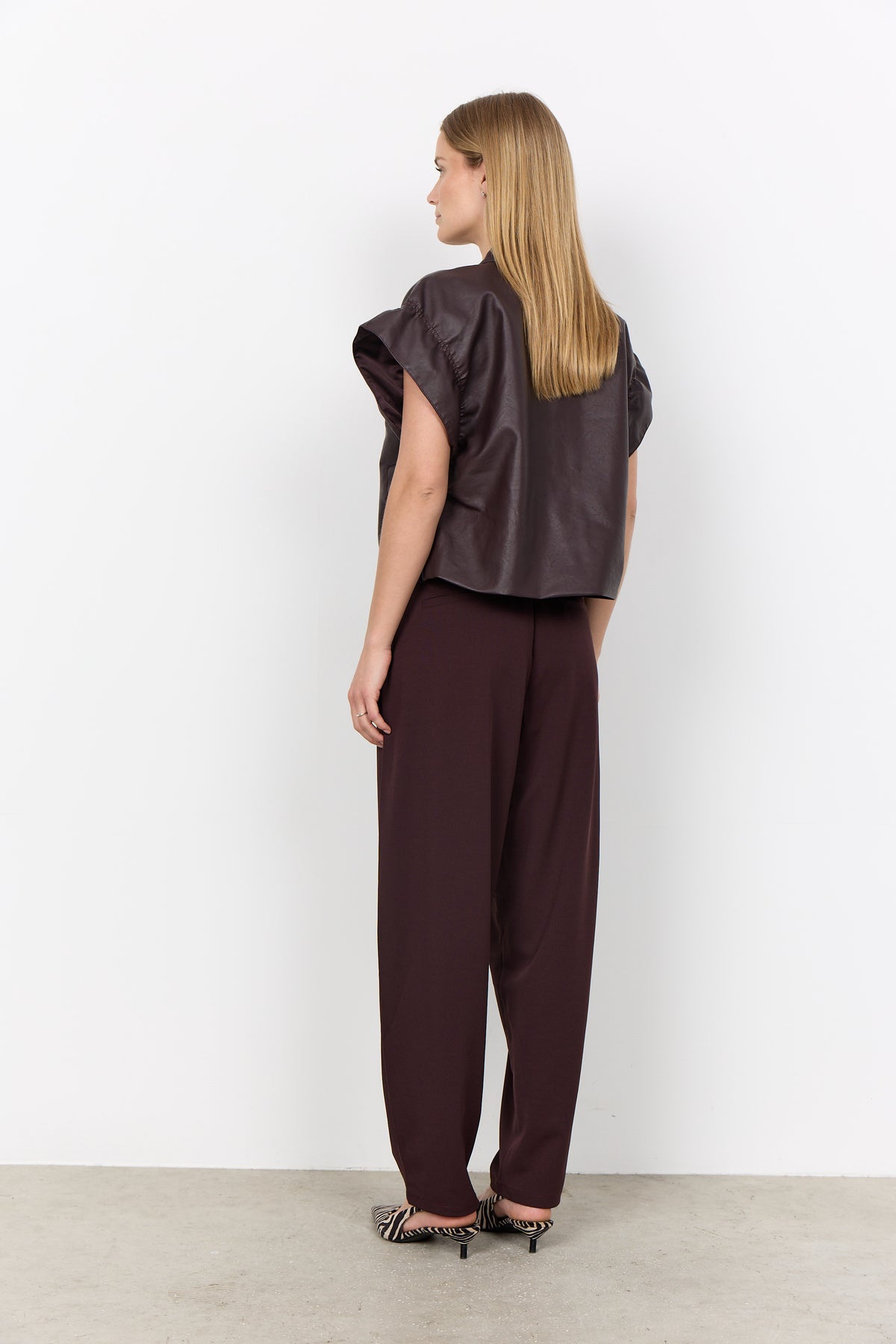 Woman wearing a dark brown outfit against a white background