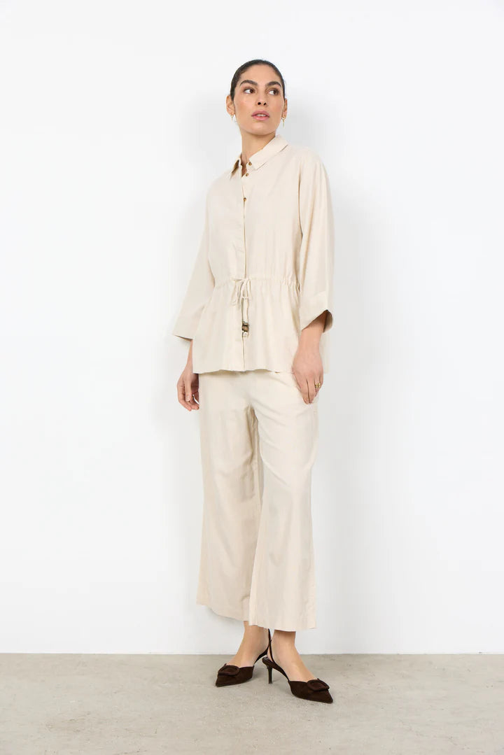 Woman wearing a beige outfit with a white background