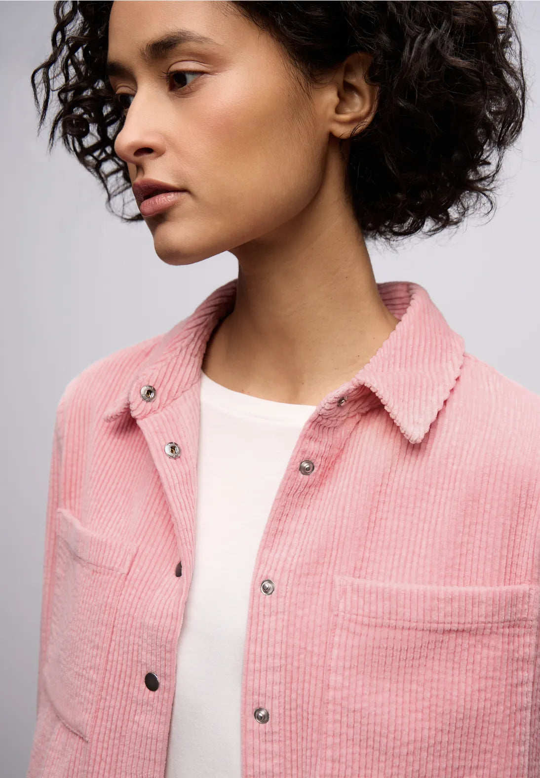 Person wearing a pink corduroy shirt against a gray background