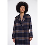 A woman wearing a navy and black plaid blazer with a notched lapel, shown against a plain light gray studio background.