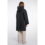 A person shown from the back wearing a long black hooded coat over light beige pants, photographed against a plain white studio background.
