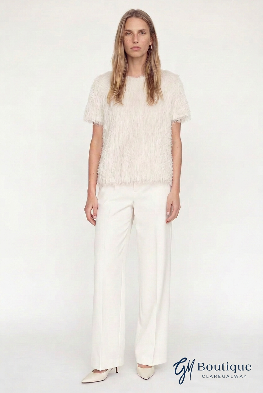 A woman modeling a short-sleeve cream textured top and matching cream wide-leg trousers against a plain light background, with a 'GM Boutique Clarendelgway' logo in the bottom right corner.