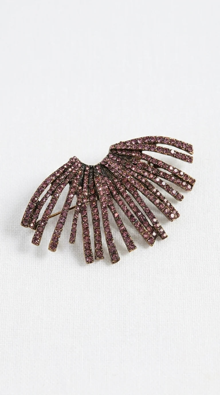A vintage-style brooch featuring multiple curved, fringe-like strands set with sparkling dark pinkish-brown rhinestones, displayed on a clean white textured background.