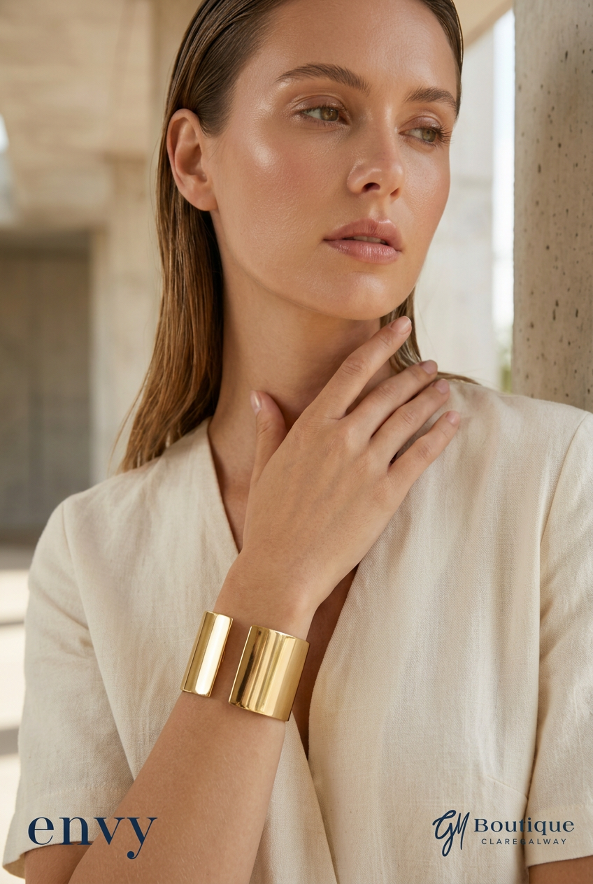 styling preview of a model wearing the Envy gold-tone wide cuff bracelet with both logos