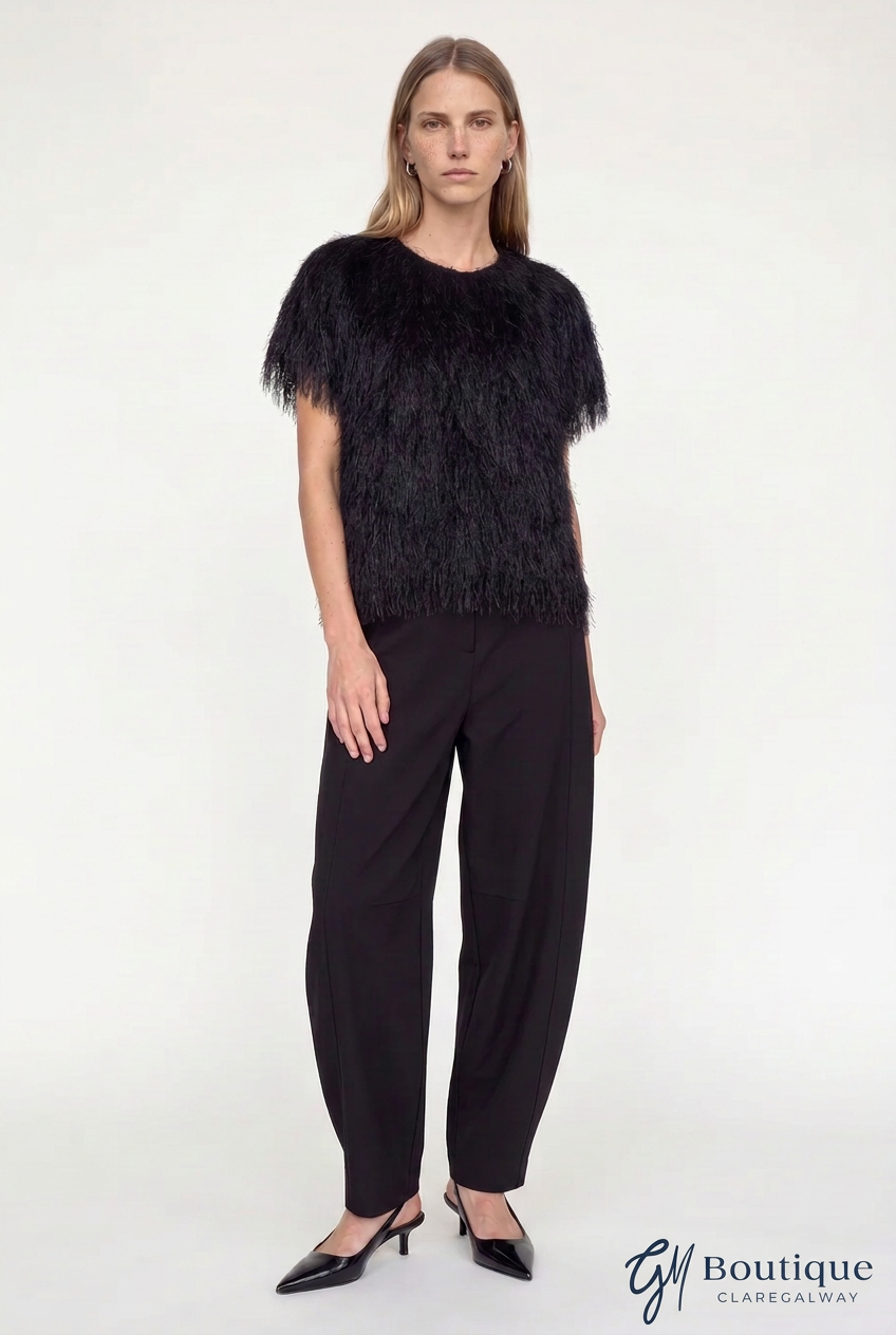 A model wearing a black feather-trimmed short-sleeve top and black wide-leg trousers, standing against a plain white studio background. The 'GM Boutique Claregalway' logo is visible in the bottom right corner.