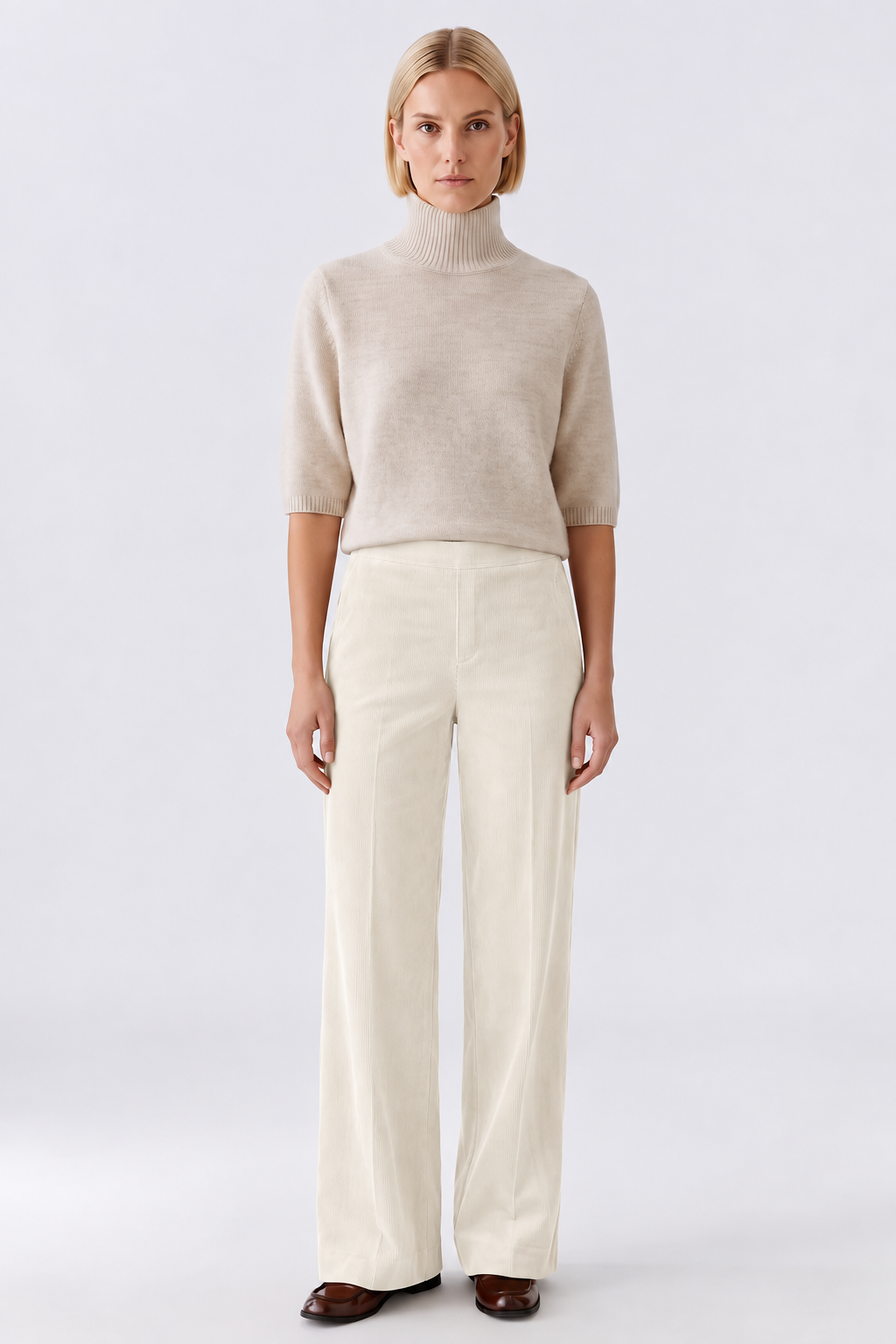 Woman wearing ivory wide-leg corduroy trousers with a high-waisted fit, styled with a cream knit top and brown loafers.