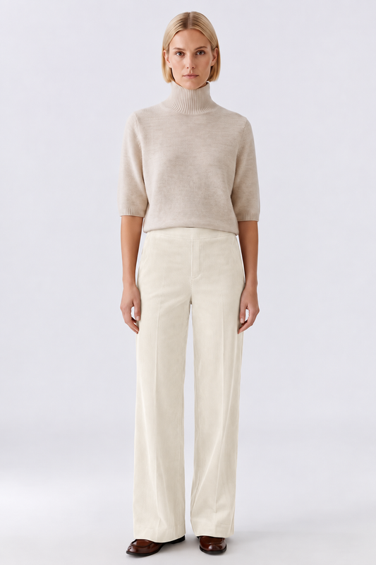 Woman wearing ivory wide-leg corduroy trousers with a high-waisted fit, styled with a cream knit top and brown loafers.