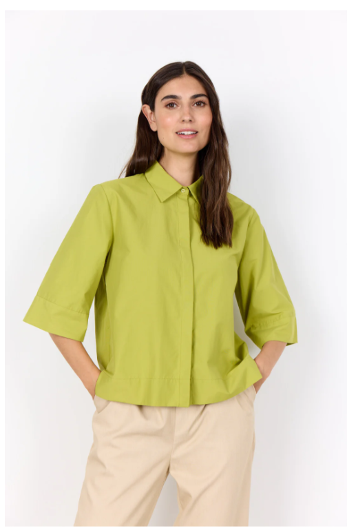 Woman wearing a green shirt and beige pants on a white background