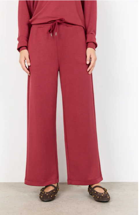 Person wearing a red outfit with wide-leg pants on a white background