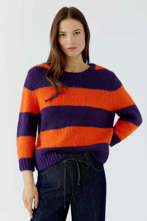 Woman wearing a striped sweater with purple and orange on a white background