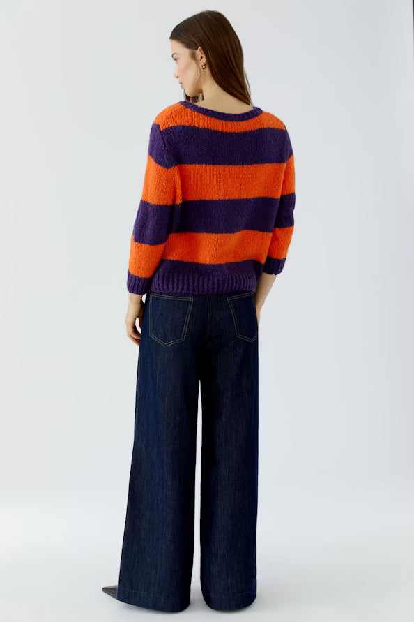 Person wearing a striped sweater and wide-leg jeans on a white background