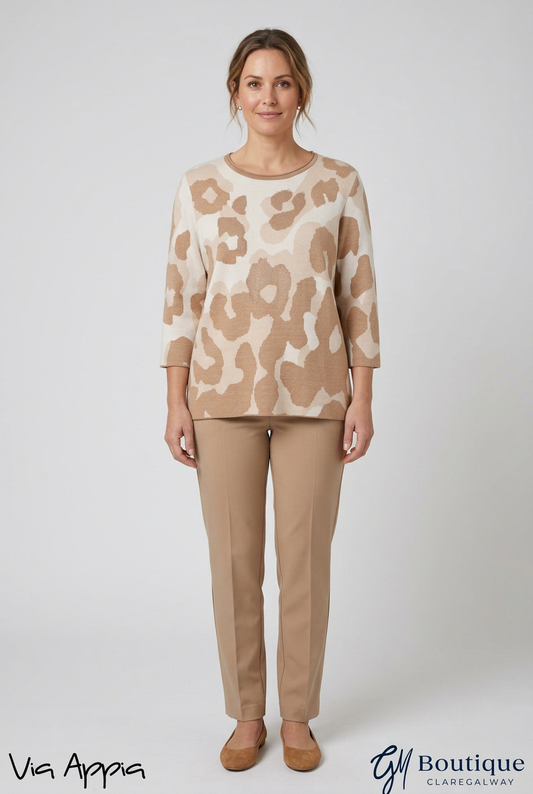 A woman stands against a light gray studio background wearing a beige and cream leopard-print long-sleeve top with tan trousers and tan flats. The text 'Vis Appa' appears at the bottom left, and 'Boutique ClaneGalway' is at the bottom right.