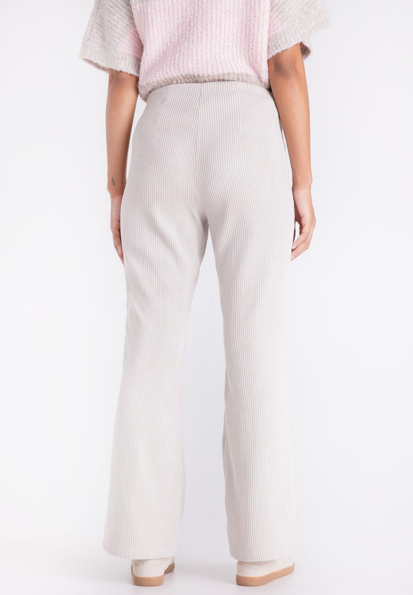 A person shown from the back wearing light beige wide-leg ribbed trousers, a pink ribbed short-sleeve top, and beige shoes against a plain white studio background.