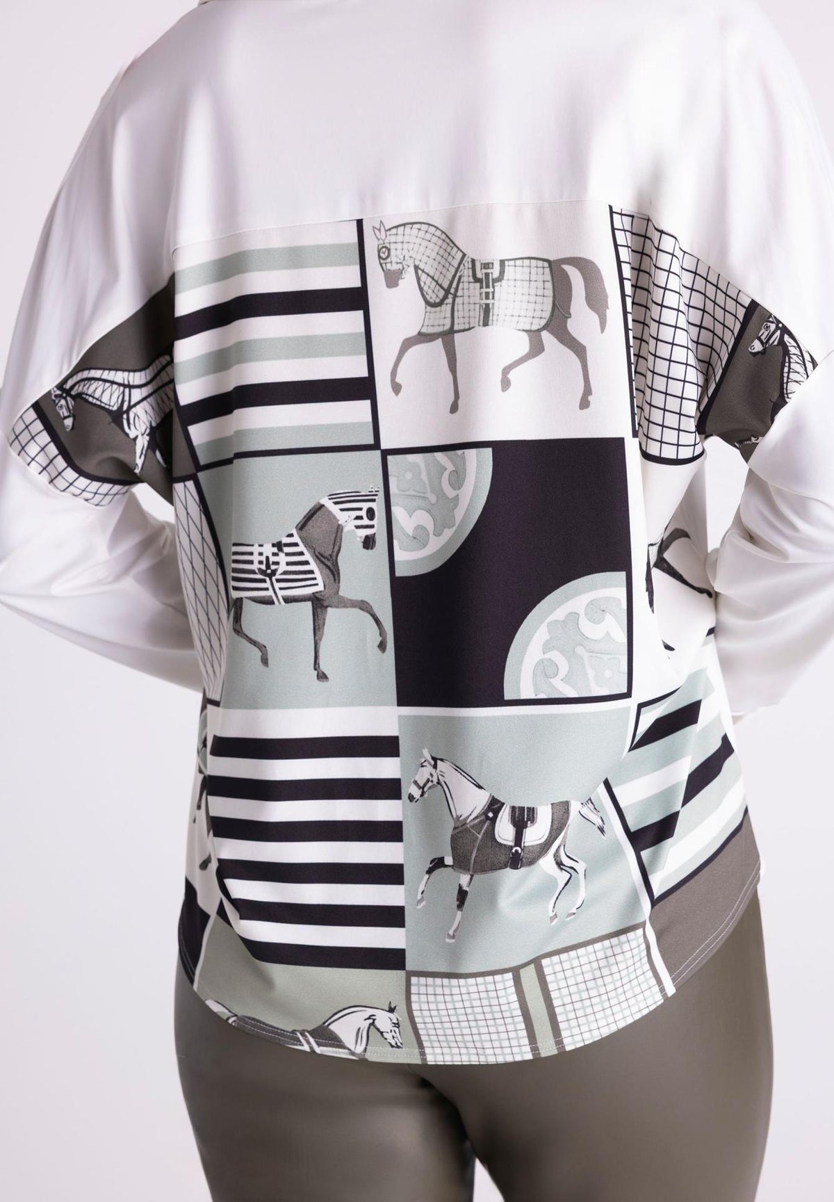 A white long-sleeve blouse with a large patchwork back panel featuring black and gray horse illustrations, stripes, and geometric patterns, shown on a model from the back.