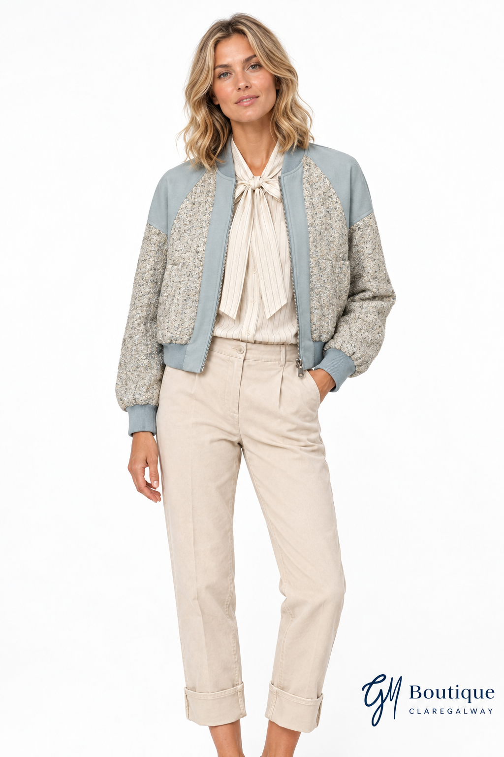 Blonde model wearing the Mos Mosh MMbeni Bessi bomber jacket, with ivory bow blouse and sand trousers, front view